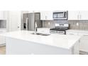 Modern kitchen featuring white cabinets, stainless steel appliances, and a spacious quartz countertop island at 22495 E 7Th Pl, Aurora, CO 80018