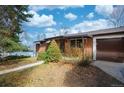 Charming brick home with a well-manicured lawn and an attached garage with brown door at 5132 Eaton St, Denver, CO 80212