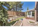 Brick home featuring a fully fenced backyard with brick patio, sunroom, grass, and mature landscaping at 7559 S Ivanhoe Cir, Centennial, CO 80112
