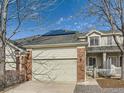 Charming home featuring a two-car garage, brick accents, solar panels, and a well-maintained front yard at 12819 E Dickensen Pl, Aurora, CO 80014