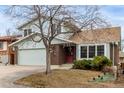 Two-story home with a brick facade, attached two car garage, and mature trees in yard at 2228 S Eldridge St, Lakewood, CO 80228