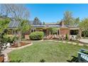 Charming brick home with solar panels, a well-manicured lawn, and a cozy front patio seating area at 805 Union Ave, Boulder, CO 80304