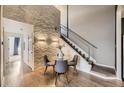 Cozy dining area features a glass table, modern chairs, a stacked stone accent wall, and staircase access at 9481 E Mansfield Ave # 301, Aurora, CO 80014