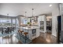 Gourmet kitchen boasts white cabinets, a large center island with seating, and stainless steel appliances at 26989 E Friend Pl, Aurora, CO 80016