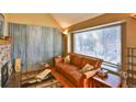 Cozy living room featuring a large window, stone fireplace, and comfortable leather sofa at 7978 Chase Cir # G, Arvada, CO 80003