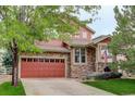 Charming two-story home with a stone and red siding exterior and an attached two-car garage at 24686 E Florida Ave, Aurora, CO 80018