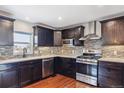 Contemporary kitchen with stainless steel appliances, dark cabinets, tile backsplash, and hardwood floors at 19739 E Wagontrail Dr, Centennial, CO 80015