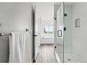 Modern bathroom featuring a glass enclosed shower, gray wood flooring, and bright white walls at 5555 E Briarwood Ave # 2604, Centennial, CO 80122