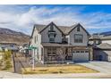 Charming two-story home with gray siding, covered porch, stone accents, mountain views, and manicured lawn at 3377 S Quartz St, Morrison, CO 80465