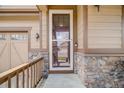 Welcoming front porch with stone accents, leading to a screened front door and attached two-car garage at 12678 Fisher Ln, Englewood, CO 80112