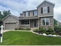 Beautiful two-story home featuring stone accents, a covered porch, and a well-manicured lawn at 7099 Cerney Cir, Castle Pines, CO 80108