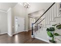 Bright foyer with hardwood floors, soaring ceiling, a staircase with white railings, and an elegant chandelier at 7099 Cerney Cir, Castle Pines, CO 80108