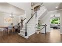 Open foyer with dark wood floors, view into dining and living rooms, and staircase with carpeted treads at 7099 Cerney Cir, Castle Pines, CO 80108
