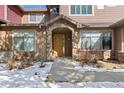 Inviting home entrance featuring a stone archway and tasteful landscaping; snow on ground at 8643 Gold Peak Dr # E, Highlands Ranch, CO 80130
