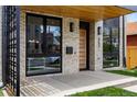 Inviting front porch with modern brickwork, wood ceiling, sleek black trim, and a contemporary wood front door at 357 S Franklin St, Denver, CO 80209