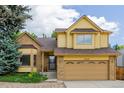 Two-story home featuring a front-facing two-car garage, brick and shingle siding, and lush landscaping at 12319 W Burgundy Ave, Littleton, CO 80127