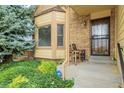 View of the front porch and front door with brick and shingle siding, bay window and green landscaping at 12319 W Burgundy Ave, Littleton, CO 80127