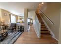Open hallway with hardwood floors, staircase with white railing, and views into the adjacent living spaces at 24661 E Layton Pl, Aurora, CO 80016