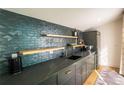 Contemporary wet bar design with stylish backsplash, wood shelves, and sleek gray cabinetry at 3600 N Pecos St, Denver, CO 80211