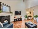 Bright living room featuring hardwood floors, a fireplace, a large mirror, and a mounted TV at 11275 Holly St, Thornton, CO 80233