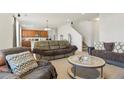 Living room with couches, coffee table, and view into kitchen and staircase at 334 Feather Pl, Lochbuie, CO 80603