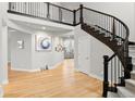 Bright foyer showcasing a hardwood floor, staircase with dark wood railing, and art-adorned walls at 6614 S Vandriver Way, Aurora, CO 80016