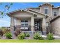 Inviting front porch of home features stone accents, railing, and swing, creating a cozy outdoor seating area at 6614 S Vandriver Way, Aurora, CO 80016