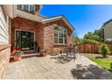 Paver patio features an outdoor dining set perfect for entertaining, with brick accent wall and well-kept lawn at 10345 Lions Heart, Lone Tree, CO 80124