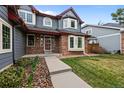 Inviting gray home featuring a brick facade, well-manicured lawn, and a walkway to the front door at 16273 E Prentice Pl, Centennial, CO 80015