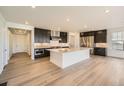 Open kitchen with dark cabinets, a large island, stainless steel appliances, and wood flooring at 2924 S Poppy St, Morrison, CO 80465