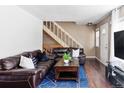 Comfortable living room with a large leather sofa, staircase, and a bright blue rug at 3820 S Fraser St, Aurora, CO 80014