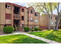 Tan apartment building featuring a stairway and manicured lawn at 8770 Corona St # 101, Denver, CO 80229