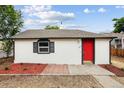 Inviting white home with a vibrant red door and manicured landscaping at 1301 Kenton St, Aurora, CO 80010