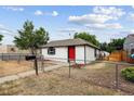 Quaint white home with a red door, fenced yard, and mailbox at 1301 Kenton St, Aurora, CO 80010