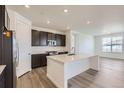 A modern kitchen is showcased with an island, stainless steel appliances, and sleek white countertops at 576 Nightsky St, Erie, CO 80516