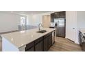 A modern kitchen is showcased with an island, stainless steel appliances, and sleek white countertops at 576 Nightsky St, Erie, CO 80516