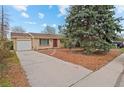 View of a one story brick home with mature tree, a driveway, and a one-car garage at 3117 Victor St, Aurora, CO 80011