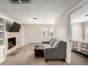 Inviting living room with a stone fireplace, built-in shelving, a comfortable sofa, and natural light from the window at 5865 E Ithaca Pl, Denver, CO 80237