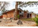Red brick ranch-style home with a covered entryway and bay window, surrounded by gravel and mature trees at 699 S Oswego St, Aurora, CO 80012