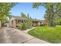 Brick home featuring lovely front yard with mature trees and wide driveway at 6940 W 63Rd Ave, Arvada, CO 80003