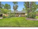 Inviting ranch-style home with mature trees, lush lawn, and a welcoming front entrance at 6940 W 63Rd Ave, Arvada, CO 80003