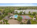 Aerial view of community pool, tennis courts, lake, and lush green surroundings at 8699 Garrison Ct, Arvada, CO 80005