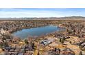 Panoramic aerial view of a community with a picturesque lake, tennis courts, and mountain views in the distance at 8699 Garrison Ct, Arvada, CO 80005