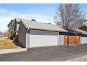 Exterior view of a two-car garage with neutral siding and a driveway at 8699 Garrison Ct, Arvada, CO 80005