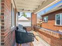 Cozy covered patio with brick walls, comfortable seating, and a view of the backyard at 1528 Holly St, Denver, CO 80220