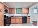 Functional kitchen with oak cabinets, tile flooring, and black appliances, providing a practical cooking space at 700 E Ellsworth Ave # 2, Denver, CO 80209