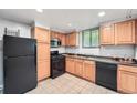 Practical kitchen with oak cabinets, black appliances, tile flooring, and ample counter space at 700 E Ellsworth Ave # 2, Denver, CO 80209