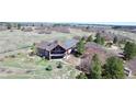 The rear of this home features solar panels, a full-length patio, and mature trees in a large yard at 12984 Crowfoot Springs Rd, Larkspur, CO 80118