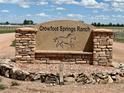 The stone Crowfoot Springs Ranch sign has stone trim and is surrounded by landscaping at 12984 Crowfoot Springs Rd, Larkspur, CO 80118