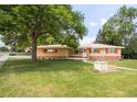 Charming brick home with a well-manicured lawn and a beautiful mature tree at 5099 S Linden Dr, Englewood, CO 80110